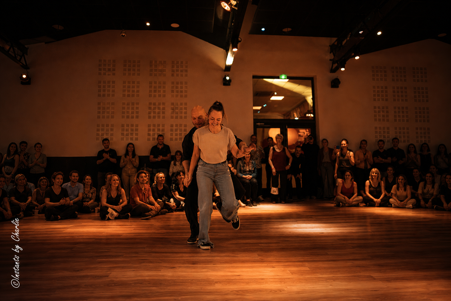 Danseuse souriante entraînée par son partenaire au centre de la piste